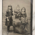 Lot 166 - Antique 1/4 Plate Tintype Photograph Of Two Young Girls In Matching Dresses Posed In Studio Beach Scene With Floral Bouquet And Coastal Background