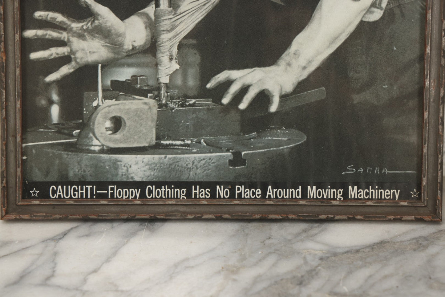 Lot 233 - Vintage Industrial Safety Photograph “Caught!—Floppy Clothing Has No Place Around Moving Machinery,” Signed Sarra, In Gray Painted Frame, 11-1/8" x 12-1/8"