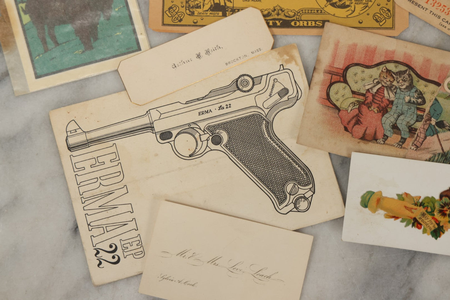 Lot 242 - Grouping Of 15 Antique And Vintage Mixed Ephemera Scraps Including Novelty Space Money From Neptune, 1882 Award Of Merit, Hand Motif Calling Cards, New England Jewelry Co. Coupon, Cat Booklet, Yellowstone Decal, And Erma EP22 Pistol Booklet
