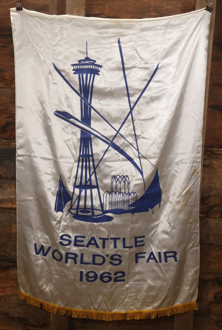 Lot 264 - Vintage Seattle World's Fair 1962 Nylon Flag Banner With Screen Printed Blue Graphics On White Field Featuring Space Needle And Other Landmarks, Yellow Fringe, Manufactured By Paramount Flag Co., San Francisco, California, 40-1/2" x 61-1/2"
