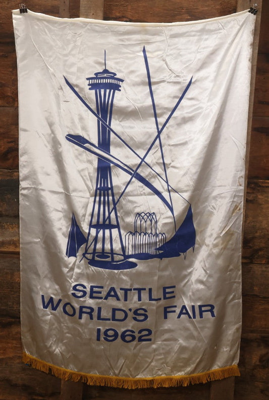 Lot 264 - Vintage Seattle World's Fair 1962 Nylon Flag Banner With Screen Printed Blue Graphics On White Field Featuring Space Needle And Other Landmarks, Yellow Fringe, Manufactured By Paramount Flag Co., San Francisco, California, 40-1/2" x 61-1/2"