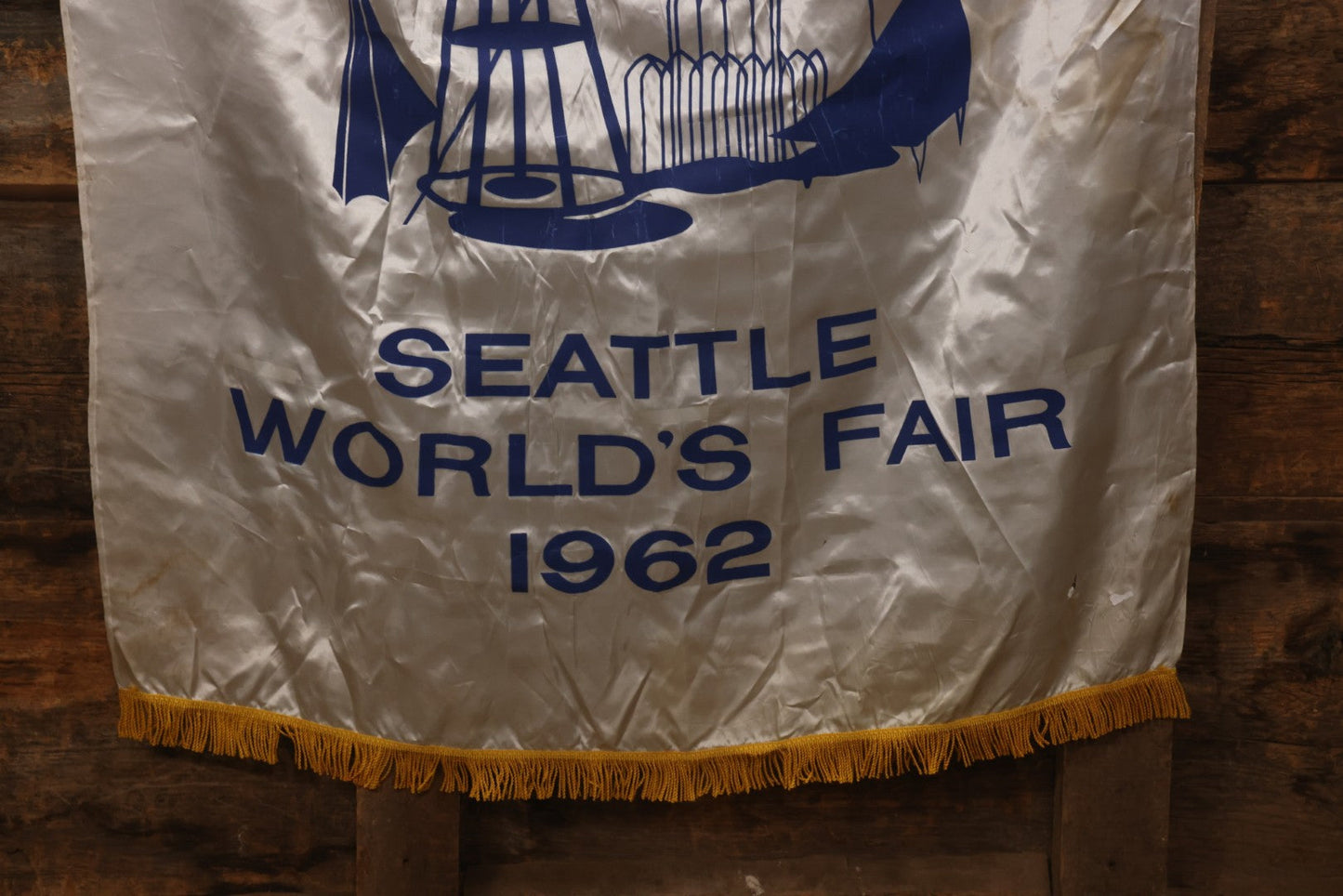 Lot 264 - Vintage Seattle World's Fair 1962 Nylon Flag Banner With Screen Printed Blue Graphics On White Field Featuring Space Needle And Other Landmarks, Yellow Fringe, Manufactured By Paramount Flag Co., San Francisco, California, 40-1/2" x 61-1/2"