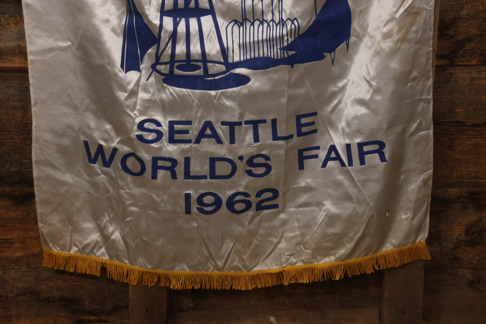 Lot 264 - Vintage Seattle World's Fair 1962 Nylon Flag Banner With Screen Printed Blue Graphics On White Field Featuring Space Needle And Other Landmarks, Yellow Fringe, Manufactured By Paramount Flag Co., San Francisco, California, 40-1/2" x 61-1/2"