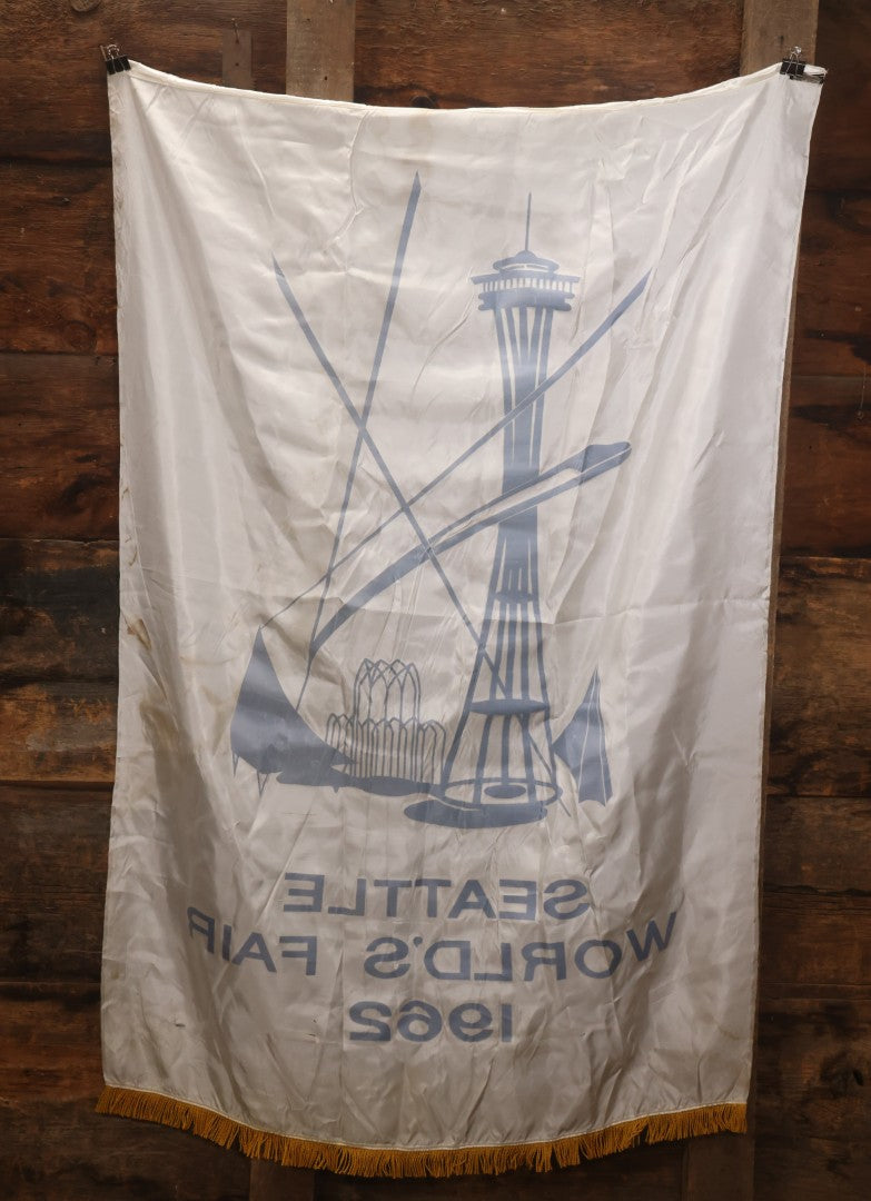 Lot 264 - Vintage Seattle World's Fair 1962 Nylon Flag Banner With Screen Printed Blue Graphics On White Field Featuring Space Needle And Other Landmarks, Yellow Fringe, Manufactured By Paramount Flag Co., San Francisco, California, 40-1/2" x 61-1/2"