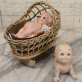 Lot 150 - Pair Of Antique Bisque Kewpie Dolls, One In Wicker Rocking Crib With Lace Bedding