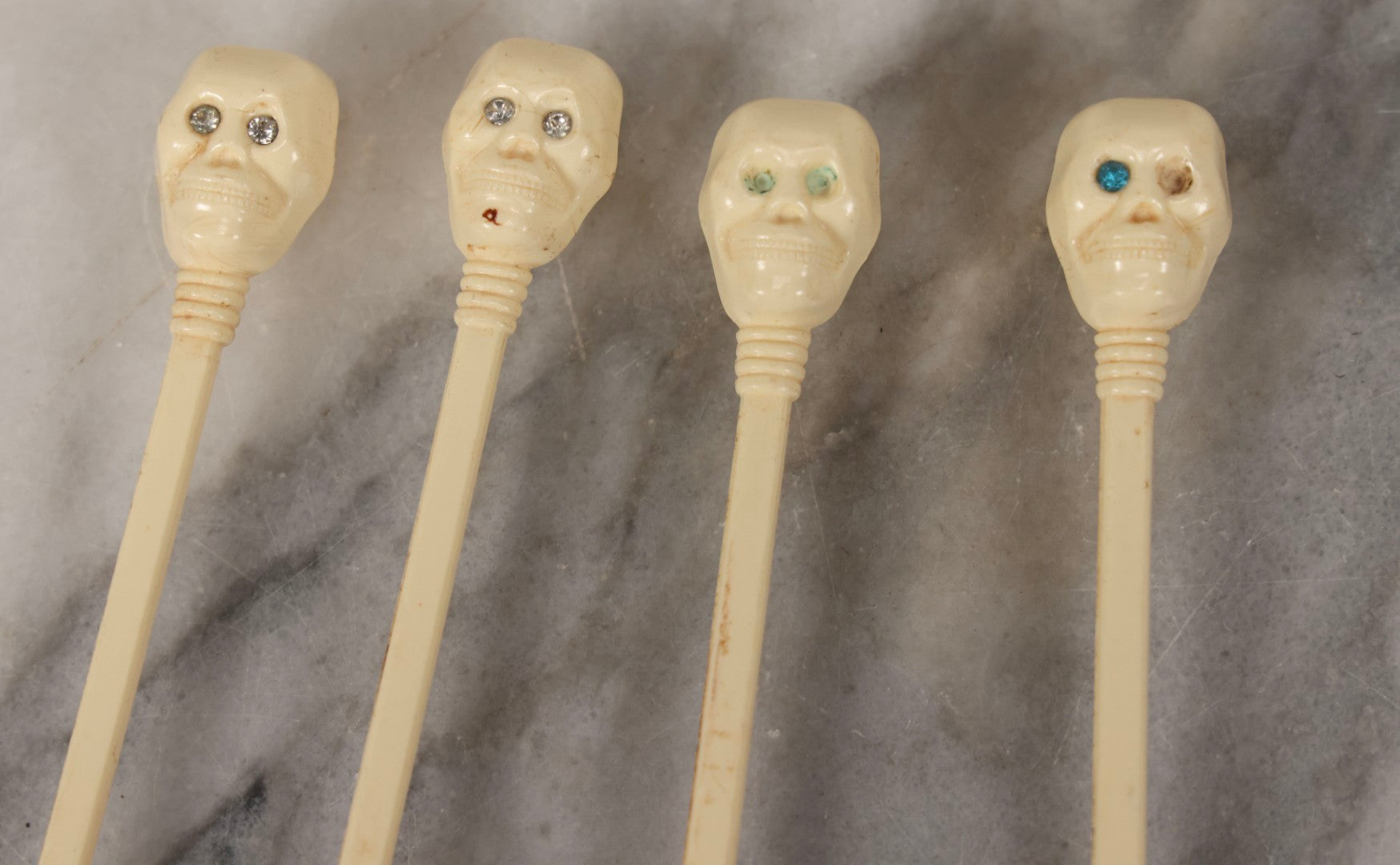 Lot 095 - Grouping Of Four Vintage Molded Plastic Skull-And-Bone Swizzle Stick Cocktail Stirrers With Rhinestone Eyes, Circa 1950s–1960s 6-3/4" L Each