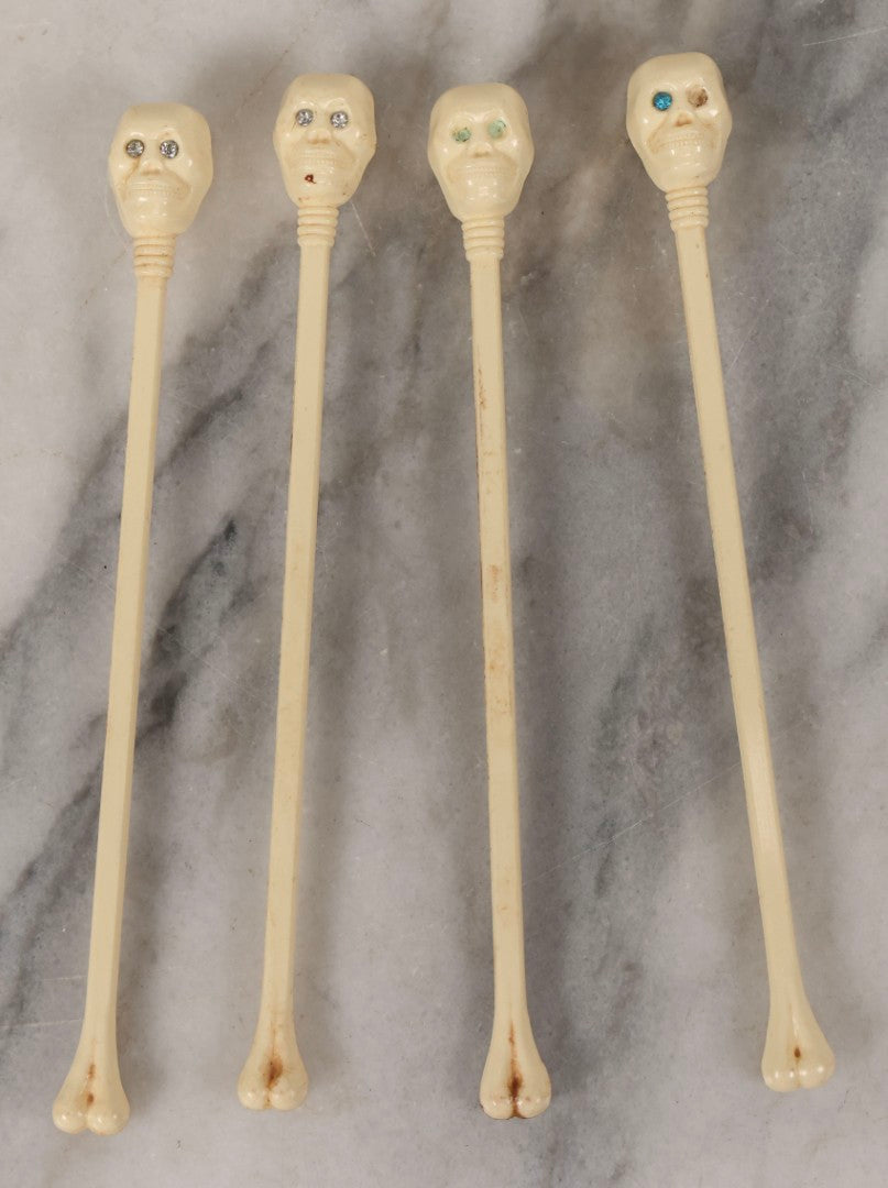 Lot 095 - Grouping Of Four Vintage Molded Plastic Skull-And-Bone Swizzle Stick Cocktail Stirrers With Rhinestone Eyes, Circa 1950s–1960s 6-3/4" L Each