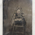Lot 104 - Antique Hidden Mother Tintype Photograph Of Baby In High Chair With Mother Or Assistant Conspicuously Concealed Beneath Floral Blanket Behind Chair