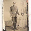 Lot 108 - Antique Tintype Photograph Of Uniformed Militiaman In Double-Breasted Coat With Shoulder Scales And Sword, Kepi On Pedestal, In Studio Setting