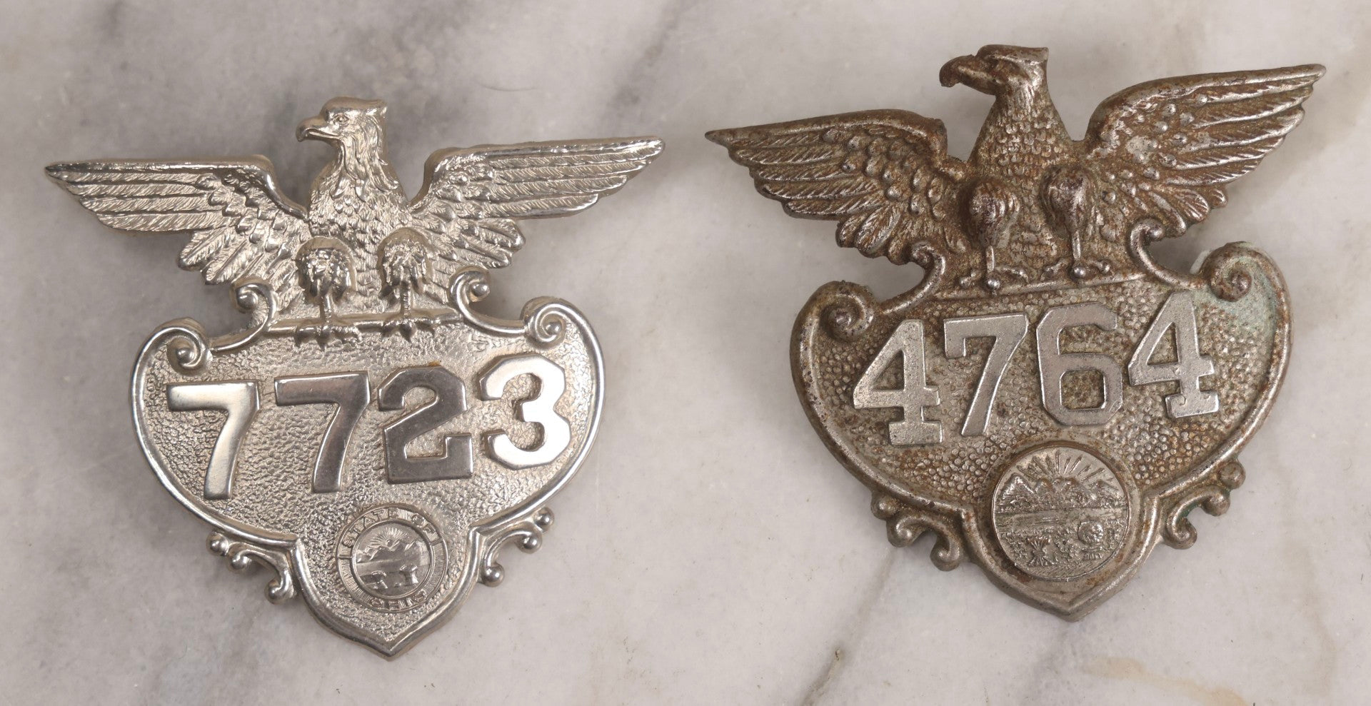 Lot 284 - Pair Of Vintage Ohio Police Patrolman's Standard Wreath Badges With Eagle Design, Numbered 4764 And 7723