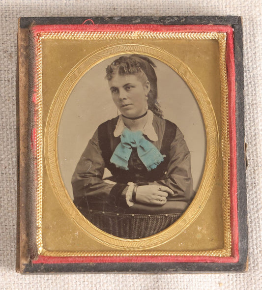 Lot 077 - Antique 1/6th Plate Tintype Photograph, Portrait Of A Young Woman With Hand-Tinted Blue Bow And Ringlet Curls, In Half Leatherette Case