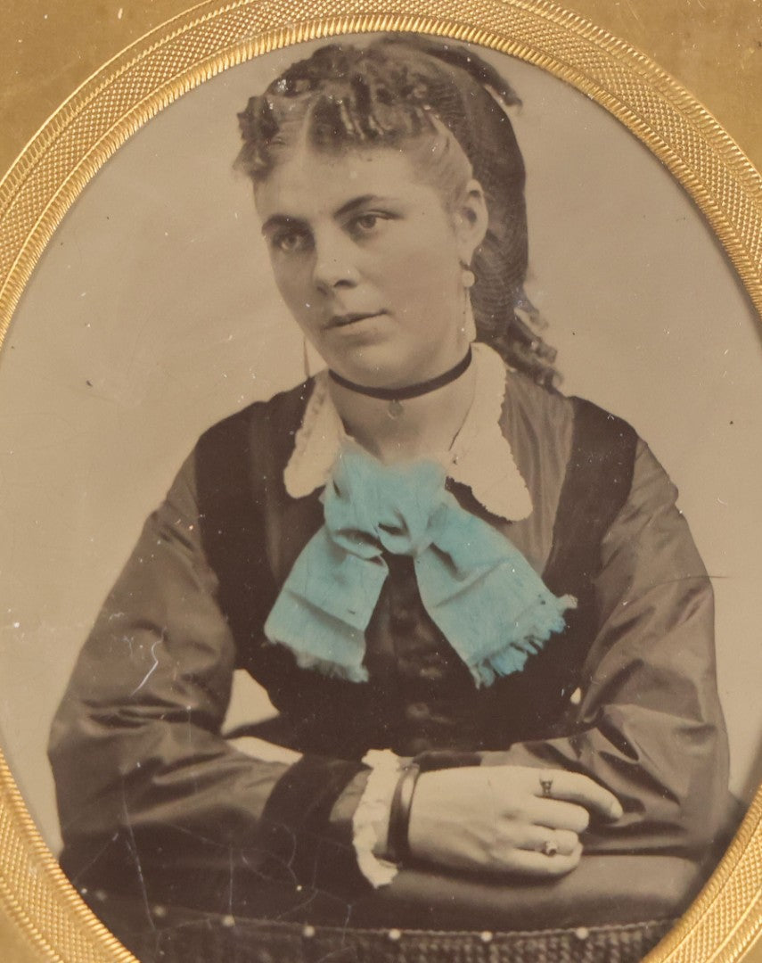Lot 077 - Antique 1/6th Plate Tintype Photograph, Portrait Of A Young Woman With Hand-Tinted Blue Bow And Ringlet Curls, In Half Leatherette Case
