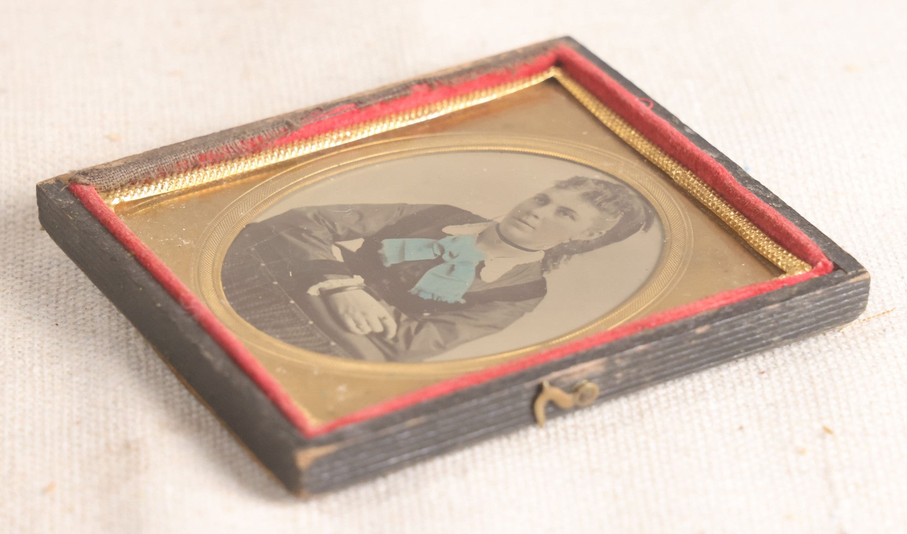 Lot 077 - Antique 1/6th Plate Tintype Photograph, Portrait Of A Young Woman With Hand-Tinted Blue Bow And Ringlet Curls, In Half Leatherette Case