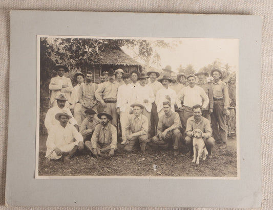Lot 096 - Antique Board-Mounted Photograph Of A Group Of Men In A Tropical Setting With A Dog