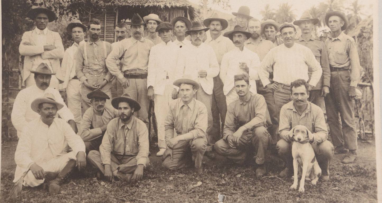 Lot 096 - Antique Board-Mounted Photograph Of A Group Of Men In A Tropical Setting With A Dog