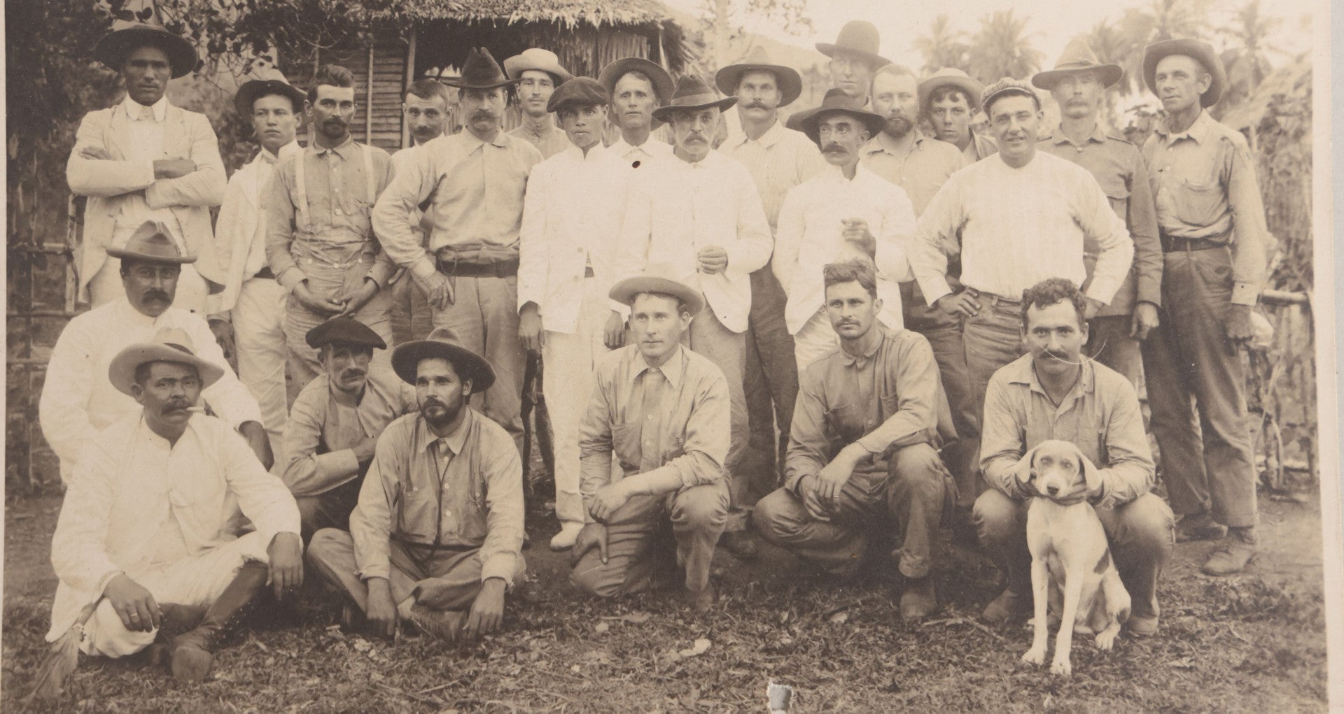 Lot 096 - Antique Board-Mounted Photograph Of A Group Of Men In A Tropical Setting With A Dog