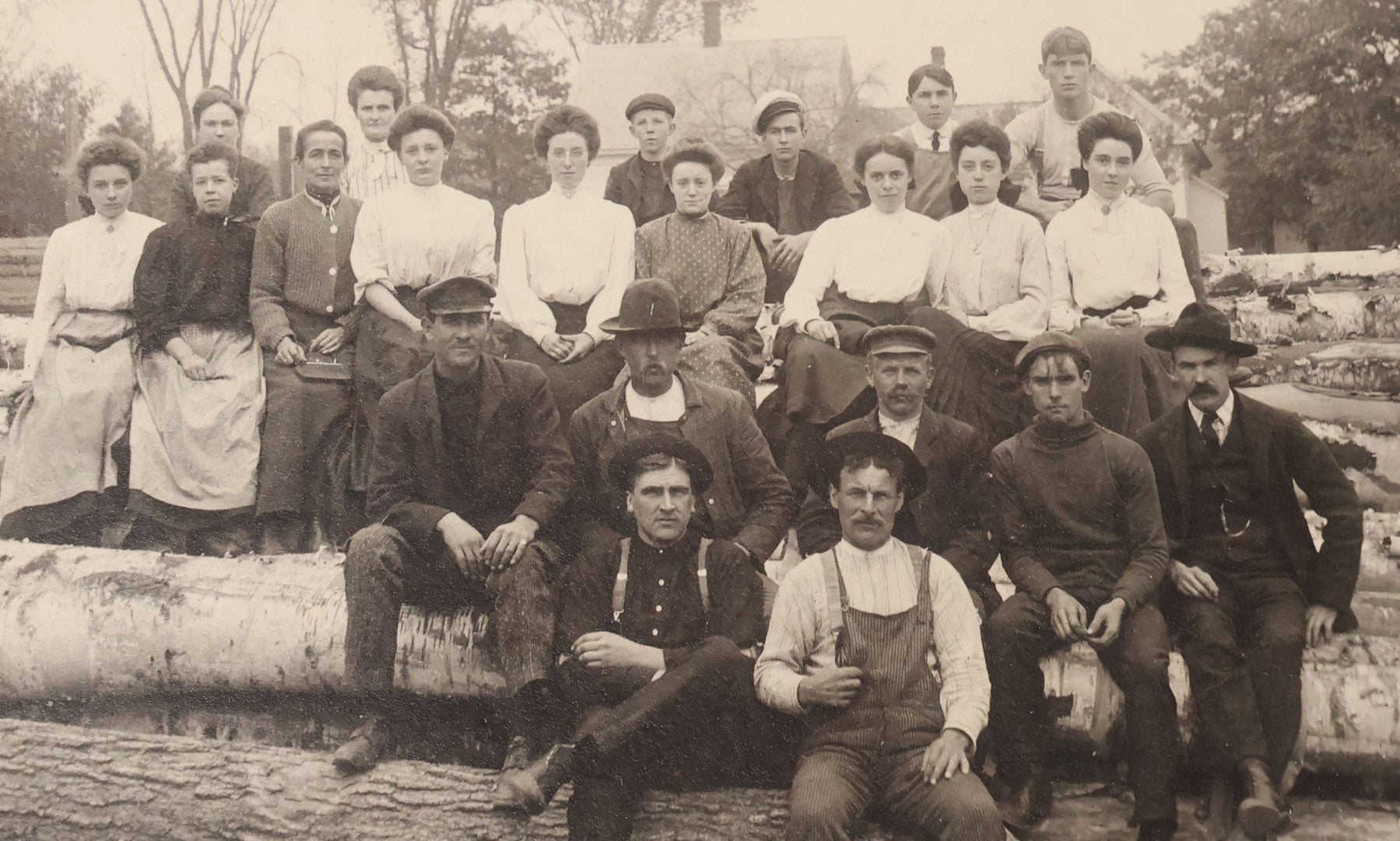 Lot 099 - Antique Board-Mounted Occupational Photograph Of A Lumber Crew, Men And Women Posed On Stacked Logs