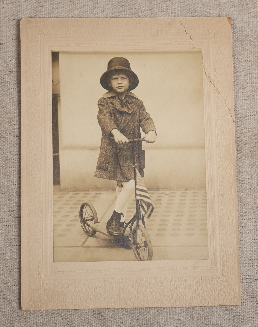 Lot 104 - Antique Board-Mounted Photograph Of A Child On A Kick Scooter With American Flag