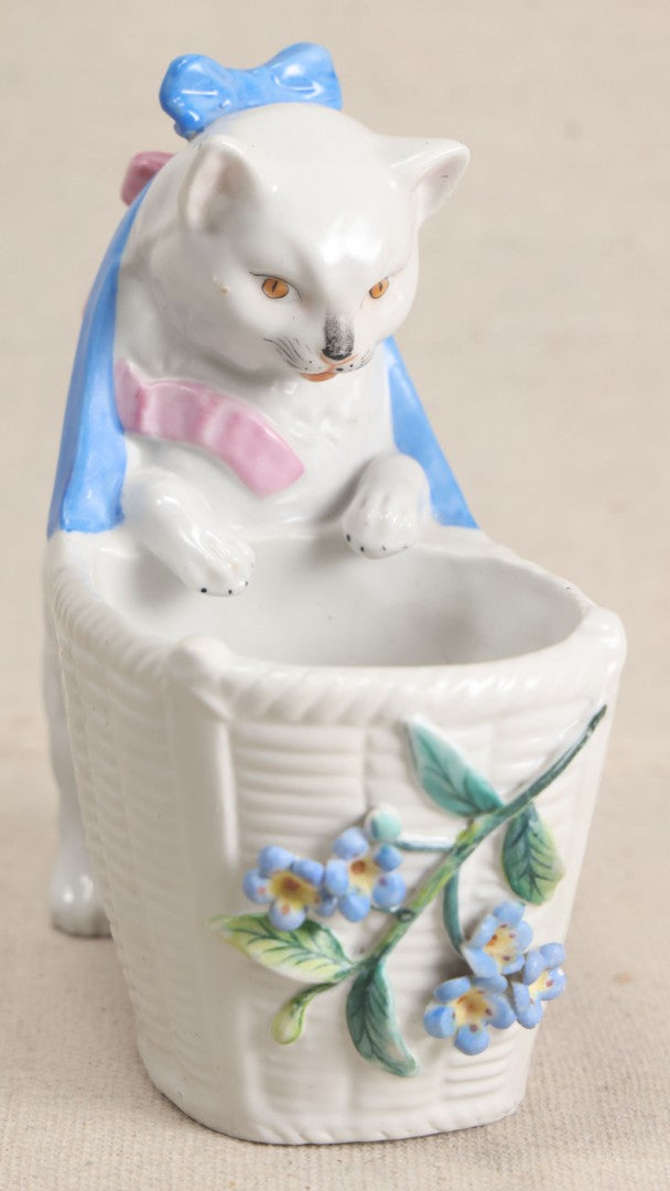 Lot 172 - Antique Porcelain Figural Cat With Basket Vase, White Cat Wearing Blue Bow And Pink Scarf With Applied Floral Decoration, Likely German