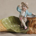Lot 176 - Antique Porcelain Figural Match Safe And Ashtray With Boy Seated On A Tree Stump And Leaf-Form Tray, 3-5/8" Height