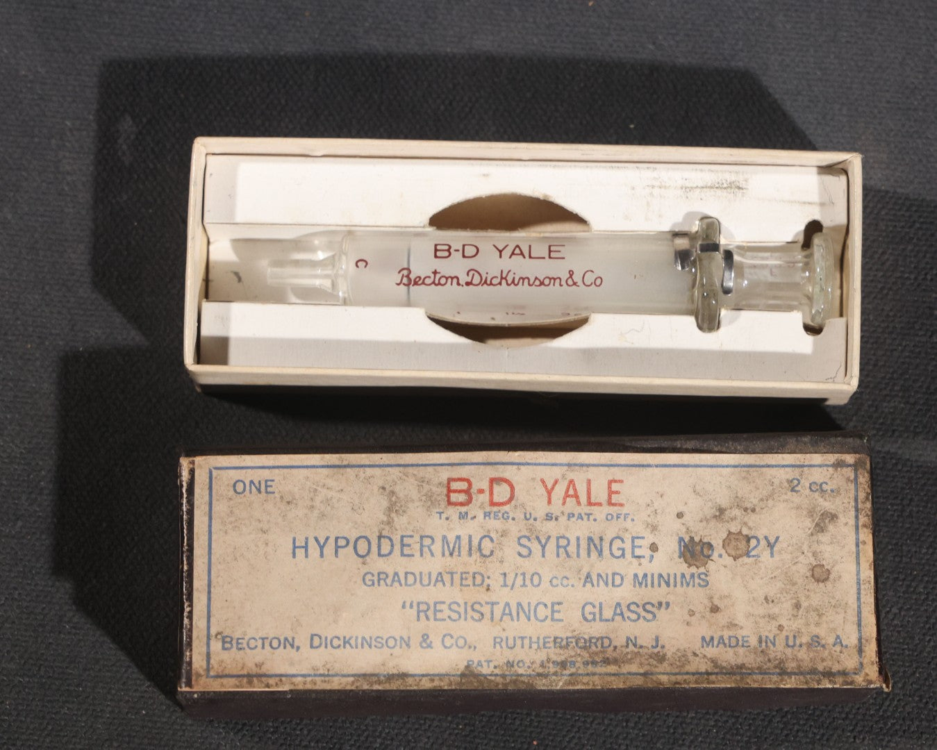 Lot 012 - Grouping Of Four Vintage Glass Medical Syringes Including Two Boxed B-D Yale Hypodermic Syringes By Becton, Dickinson And Company, Rutherford, New Jersey, One Propper Mfg. Co. 10Cc Syringe, And One B-D Yale Luer-Lok Syringe