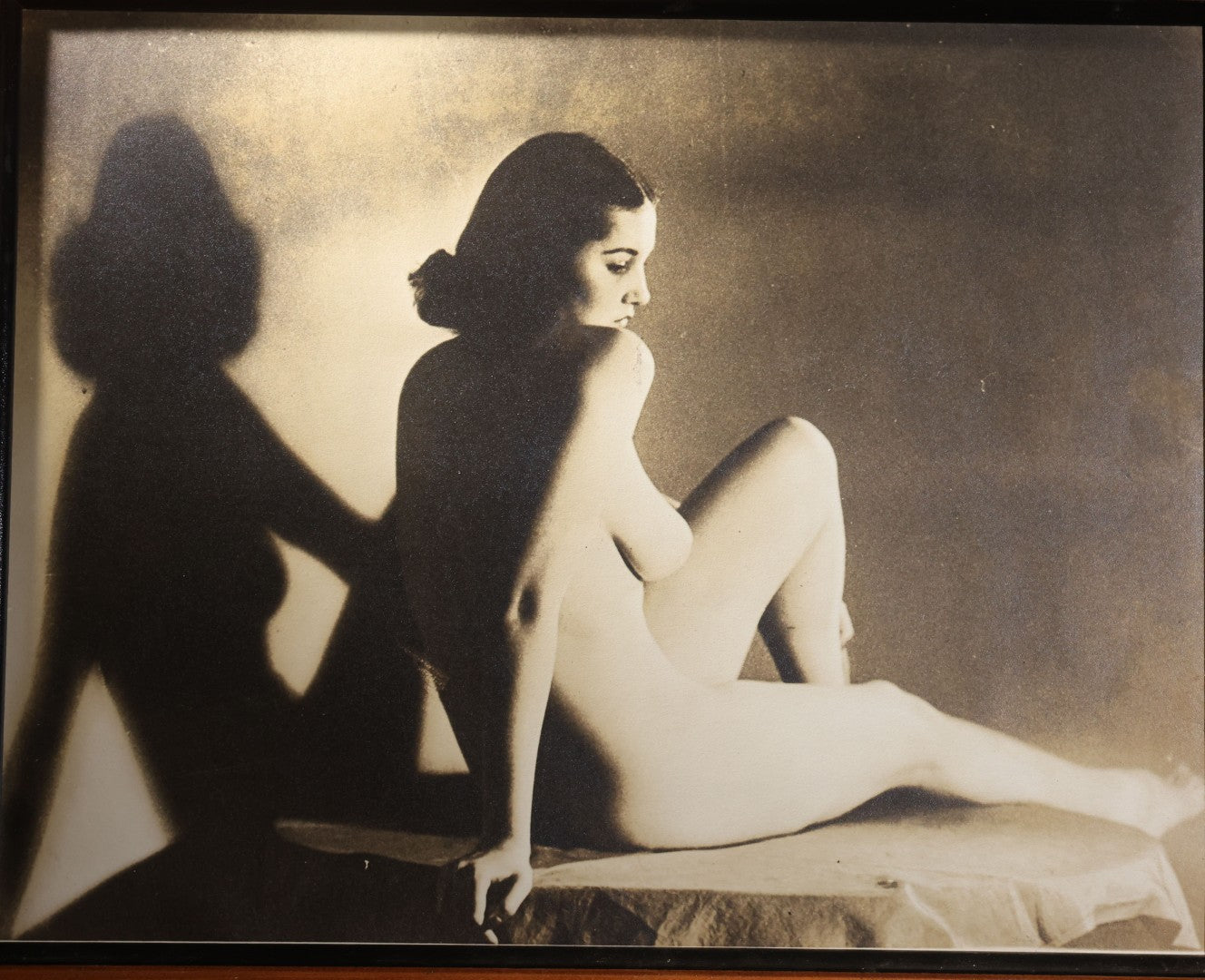 Lot 025 - Antique Framed Sepia-Tone Art Nude Photograph Of A Seated Young Woman With Dramatic Shadow, Circa 1920s-1930s