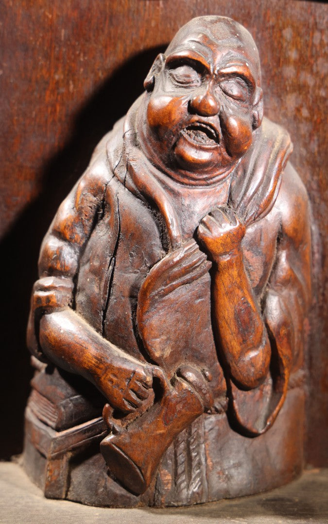 Lot 037 - Antique Folk Art Hand-Carved Wooden Figural Sculpture Of A Laughing Man With A Stein, Leaning On Books