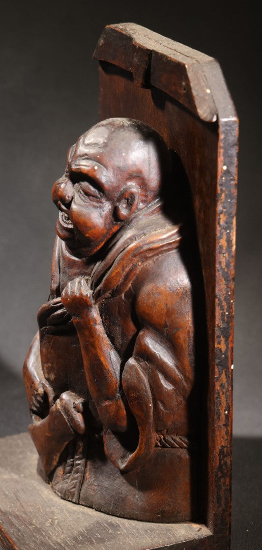 Lot 037 - Antique Folk Art Hand-Carved Wooden Figural Sculpture Of A Laughing Man With A Stein, Leaning On Books