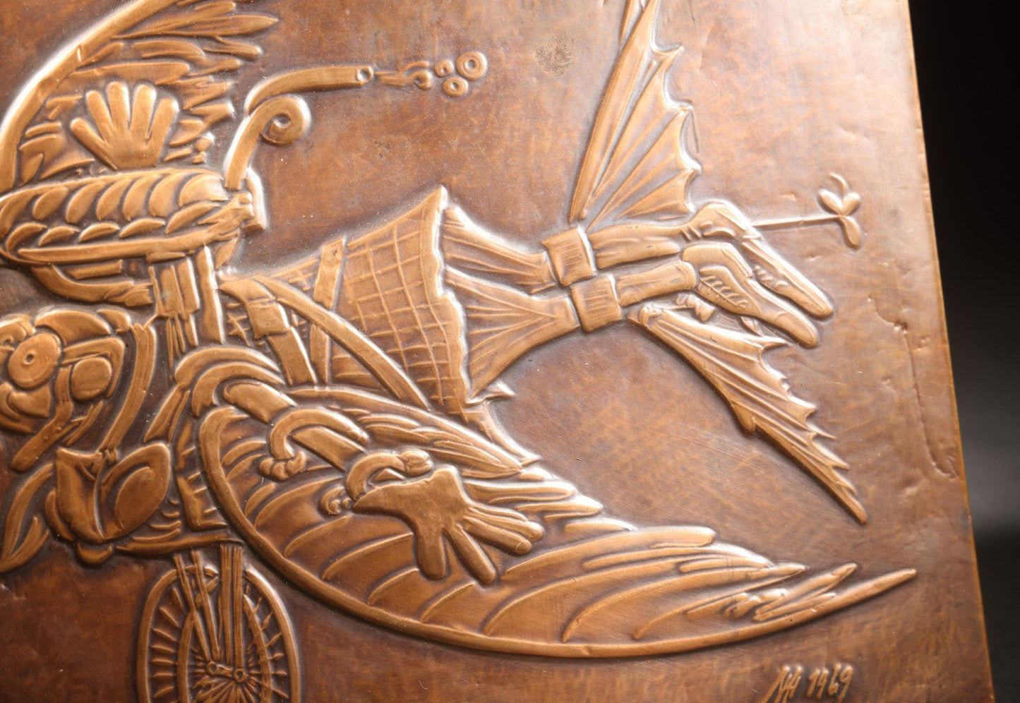 Lot 051 - Vintage Copper Repoussé Plaque On Plywood, Fantastical Winged Figure On Unicycle With Propeller, Signed And Dated 1969, Gifted From Reck, Germany, 1972, 9-1/4" x 13"