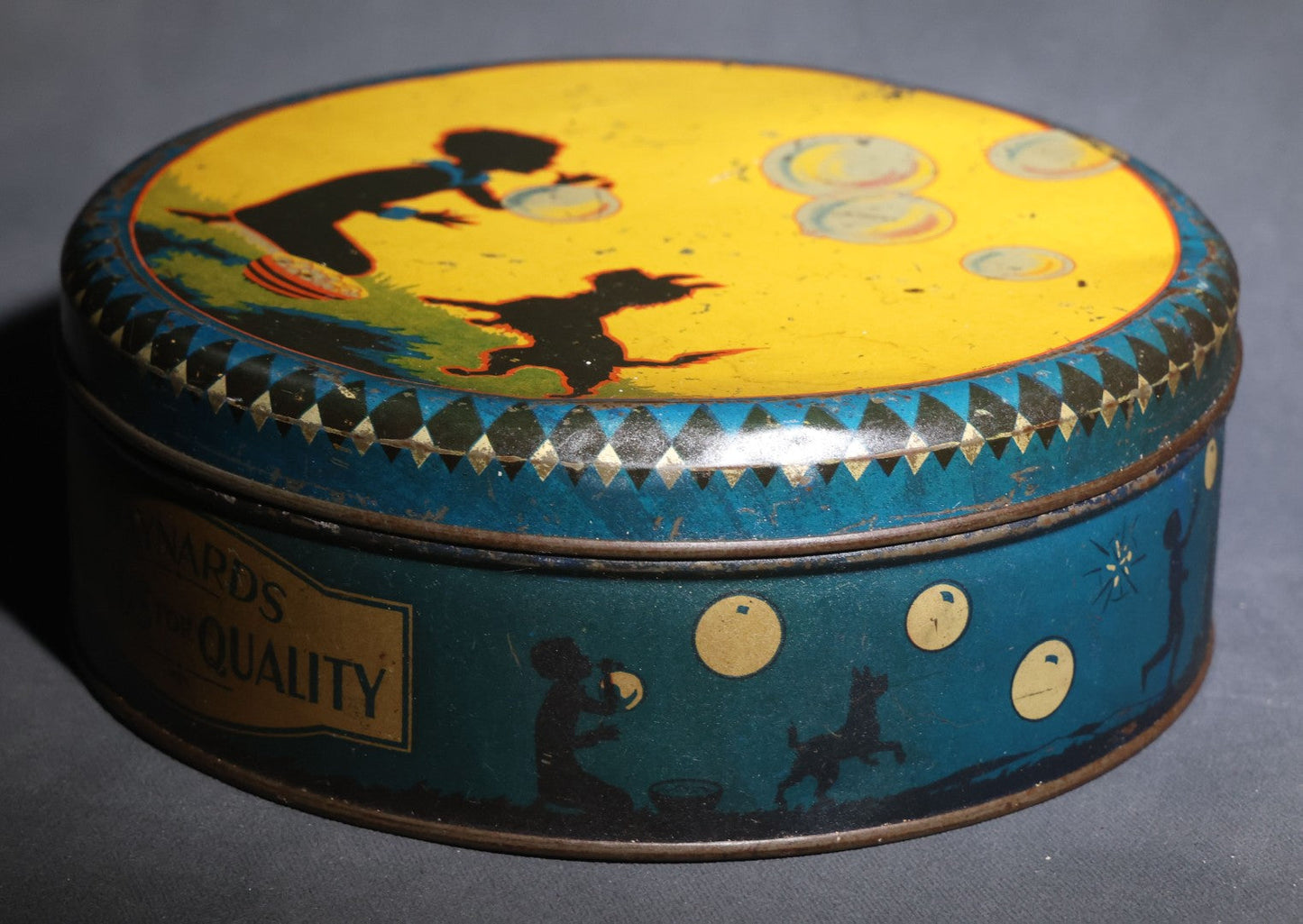 Lot 085 - Antique Maynards "Stands For Quality" Tin Lithograph Candy Tin With Silhouette Graphics Of Child Blowing Bubbles With Dog