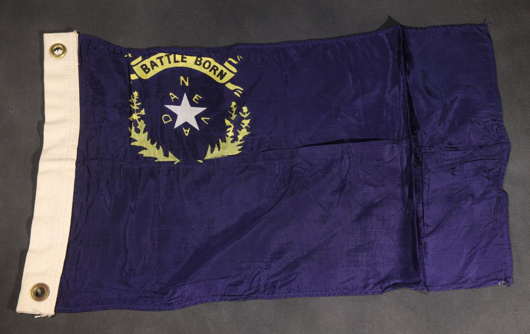 Lot 103 - Vintage Nevada State Flag, "Battle Born" Motto With Star, Sagebrush Wreath, And "Nevada" Lettering, Cobalt Blue Field, Grommeted Canvas Hoist