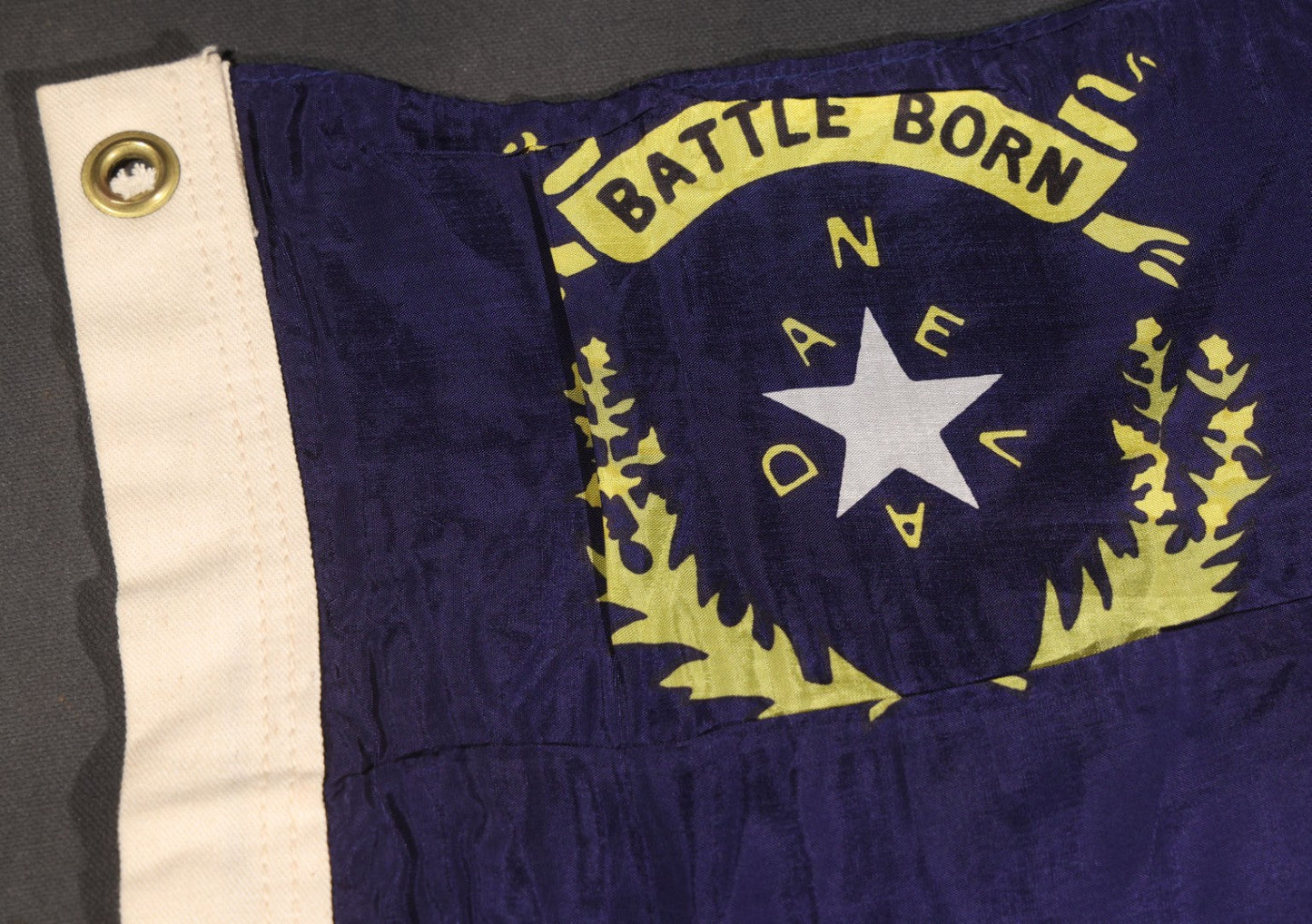 Lot 103 - Vintage Nevada State Flag, "Battle Born" Motto With Star, Sagebrush Wreath, And "Nevada" Lettering, Cobalt Blue Field, Grommeted Canvas Hoist