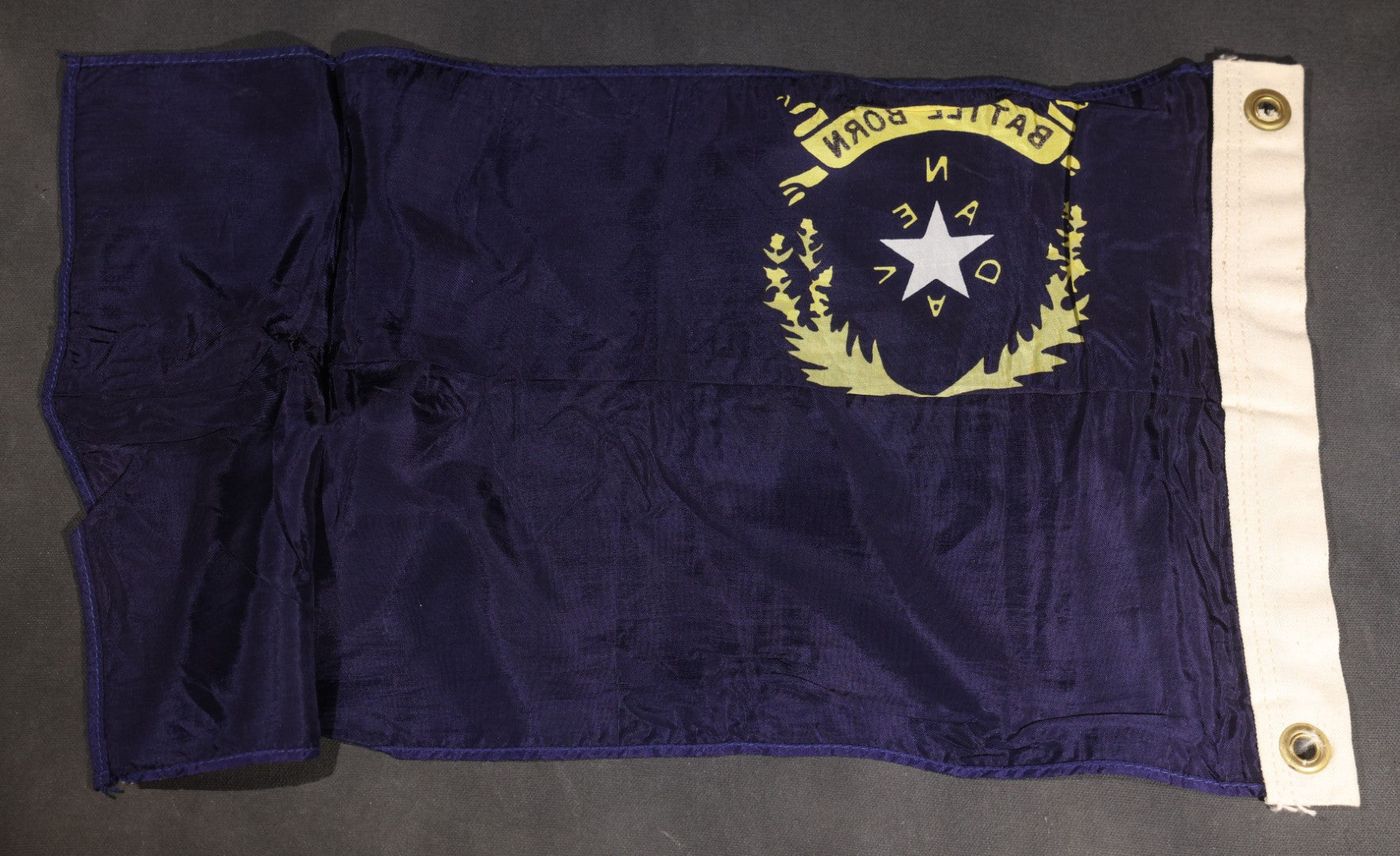 Lot 103 - Vintage Nevada State Flag, "Battle Born" Motto With Star, Sagebrush Wreath, And "Nevada" Lettering, Cobalt Blue Field, Grommeted Canvas Hoist