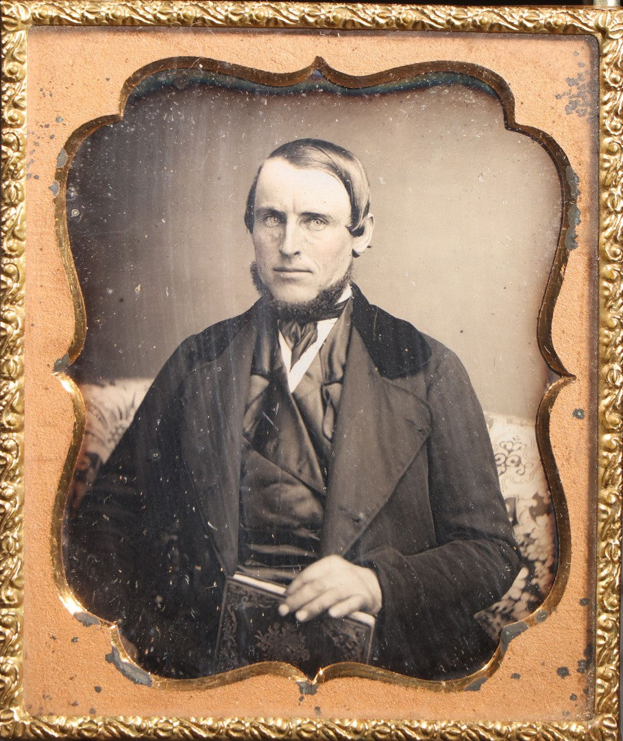 Lot 112 - Antique 1/6th Plate Daguerreotype Photograph, Uncased, Portrait Of A Middle-Aged Man With Chin Beard Holding A Book, Cartouche-Form Brass Mat
