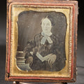 Lot 113 - Antique 1/6th Plate Daguerreotype Photograph, Half Split Leatherette Union Case With Embossed Floral Bouquet Design, Portrait Of A Middle-Aged Woman In Plaid Dress With Lace Collar, Holding Books