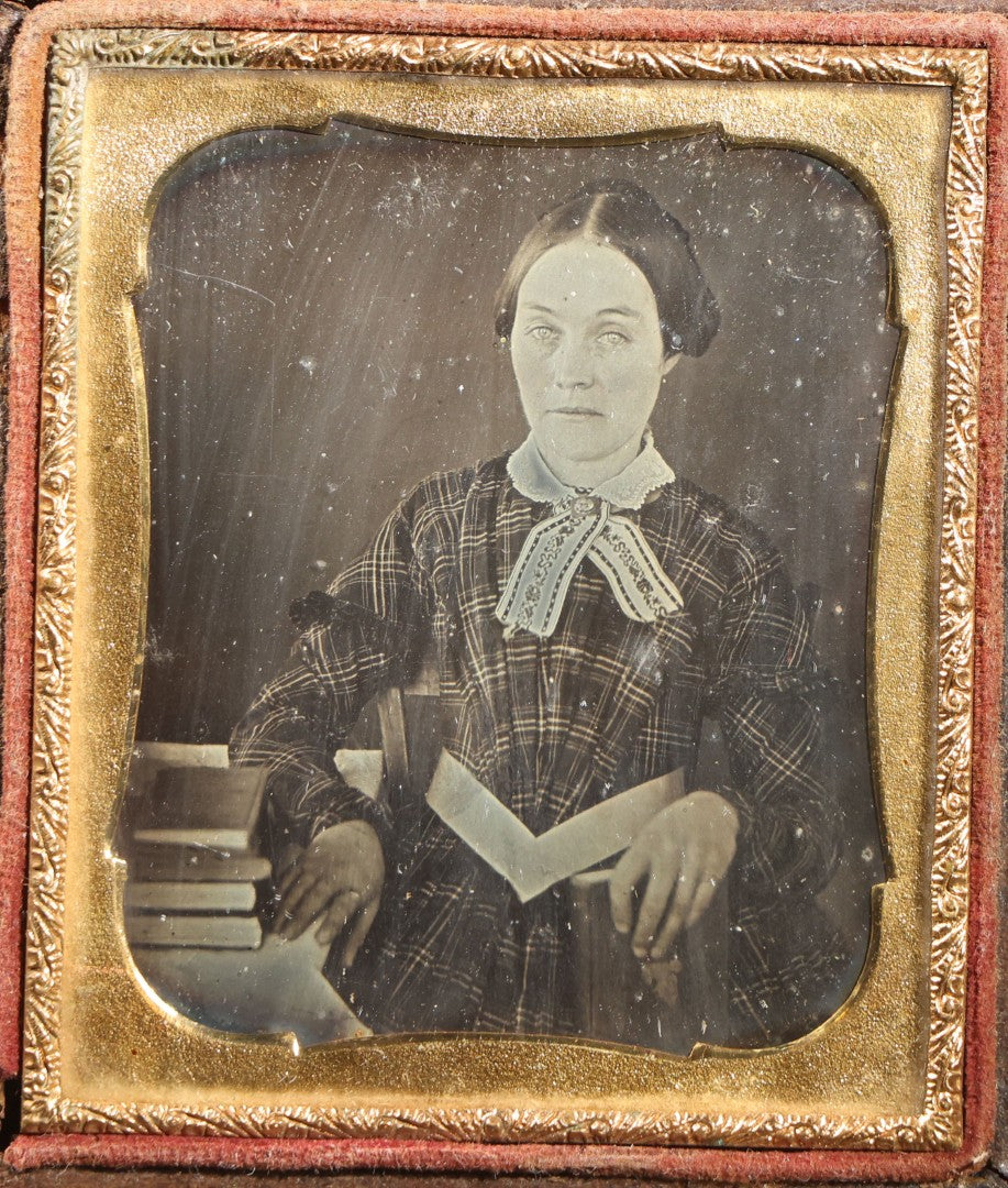 Lot 113 - Antique 1/6th Plate Daguerreotype Photograph, Half Split Leatherette Union Case With Embossed Floral Bouquet Design, Portrait Of A Middle-Aged Woman In Plaid Dress With Lace Collar, Holding Books