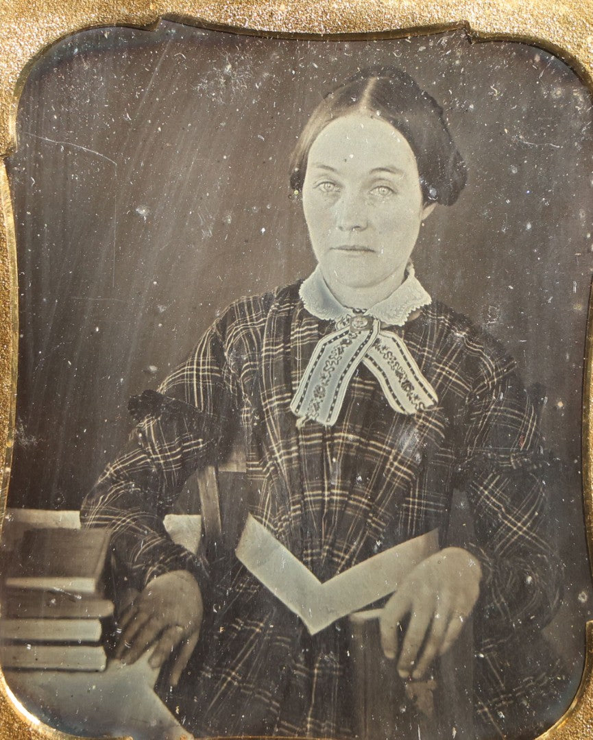 Lot 113 - Antique 1/6th Plate Daguerreotype Photograph, Half Split Leatherette Union Case With Embossed Floral Bouquet Design, Portrait Of A Middle-Aged Woman In Plaid Dress With Lace Collar, Holding Books