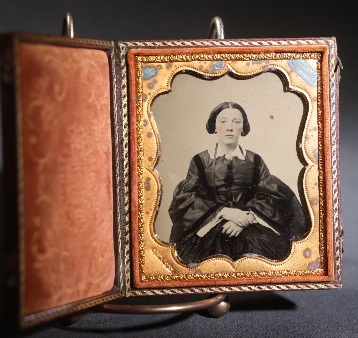 Lot 117 - Antique 1/6th Plate Ruby Ambrotype Photograph, Full Intact Leatherette Union Case, Young Woman In Dark Dress With Crossed Hands, Embossed Thistle And Floral Case Design