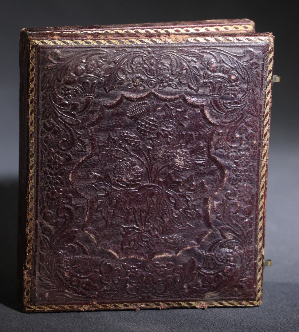 Lot 117 - Antique 1/6th Plate Ruby Ambrotype Photograph, Full Intact Leatherette Union Case, Young Woman In Dark Dress With Crossed Hands, Embossed Thistle And Floral Case Design