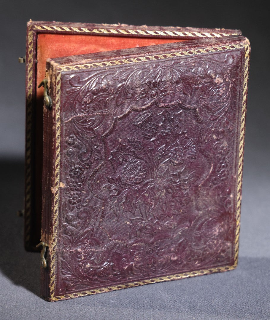 Lot 117 - Antique 1/6th Plate Ruby Ambrotype Photograph, Full Intact Leatherette Union Case, Young Woman In Dark Dress With Crossed Hands, Embossed Thistle And Floral Case Design