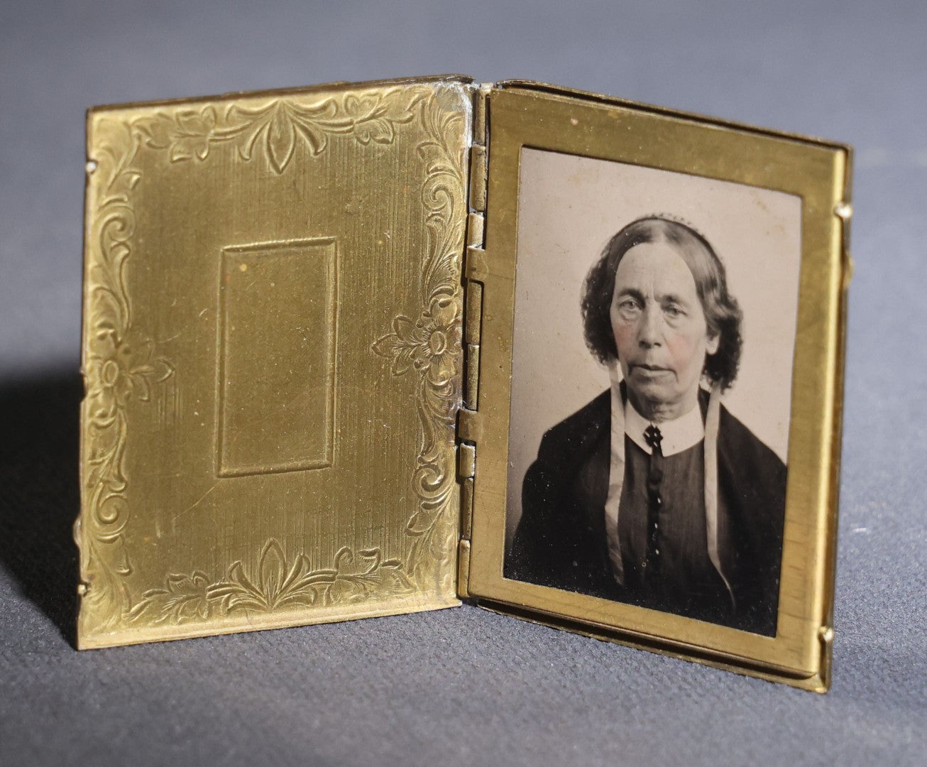 Lot 119 - Antique Tintype Photograph In Brass Book-Form Locket Case, Elderly Woman In Dark Dress, Engraved Floral And Scroll Design