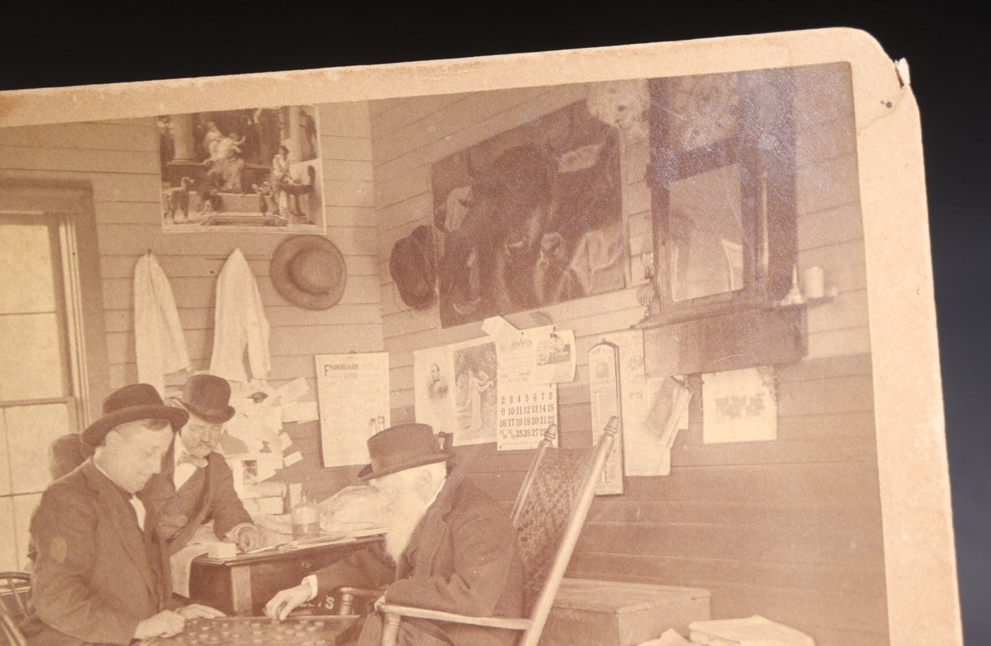 Lot 130 - Antique Boudoir-Size Cabinet Card Photograph Of Three Men Playing Checkers In A Store Interior With Pot-Belly Stove, Calendars, And Rocking Chair, Pencil-Inscribed "Uncle Ed"