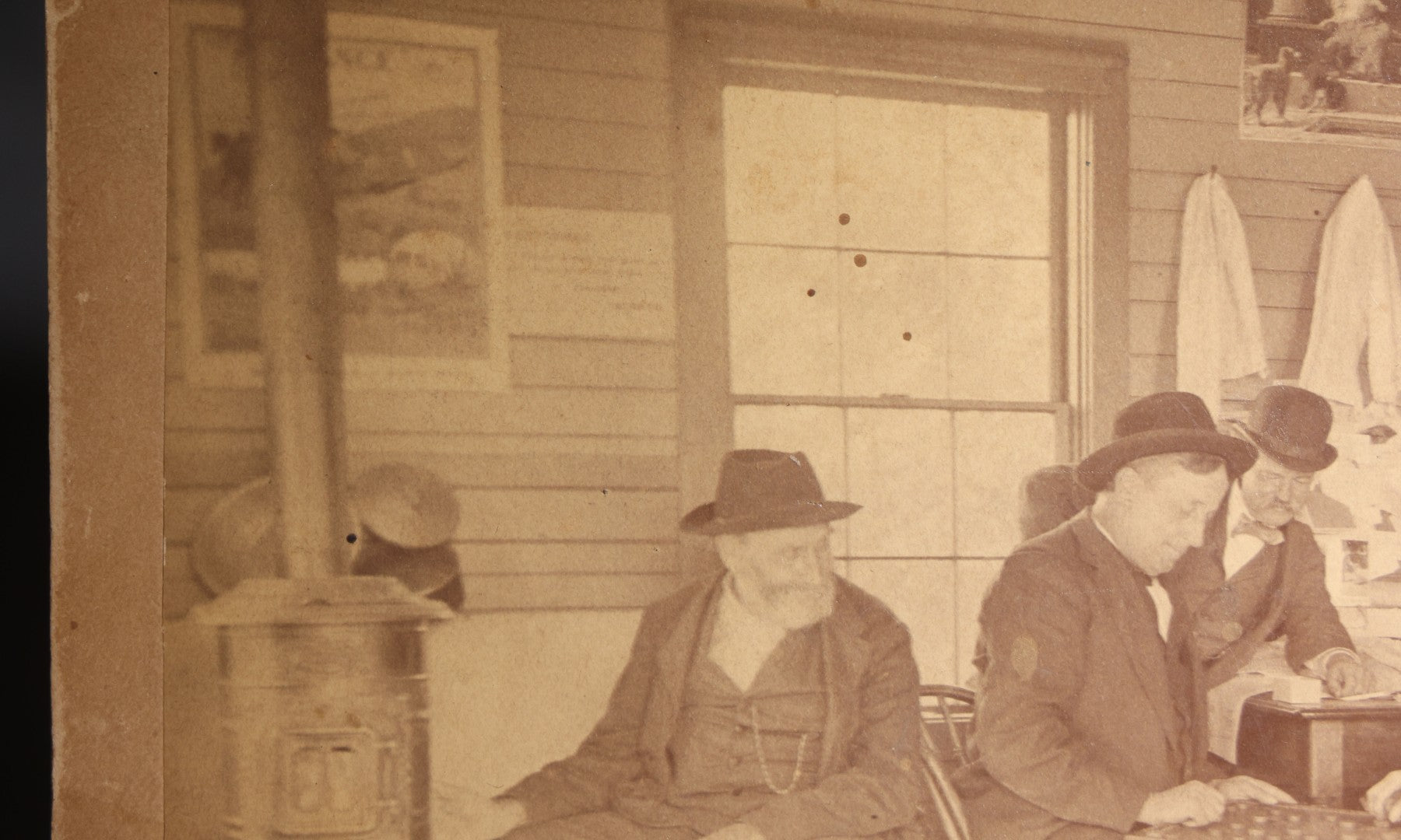 Lot 130 - Antique Boudoir-Size Cabinet Card Photograph Of Three Men Playing Checkers In A Store Interior With Pot-Belly Stove, Calendars, And Rocking Chair, Pencil-Inscribed "Uncle Ed"