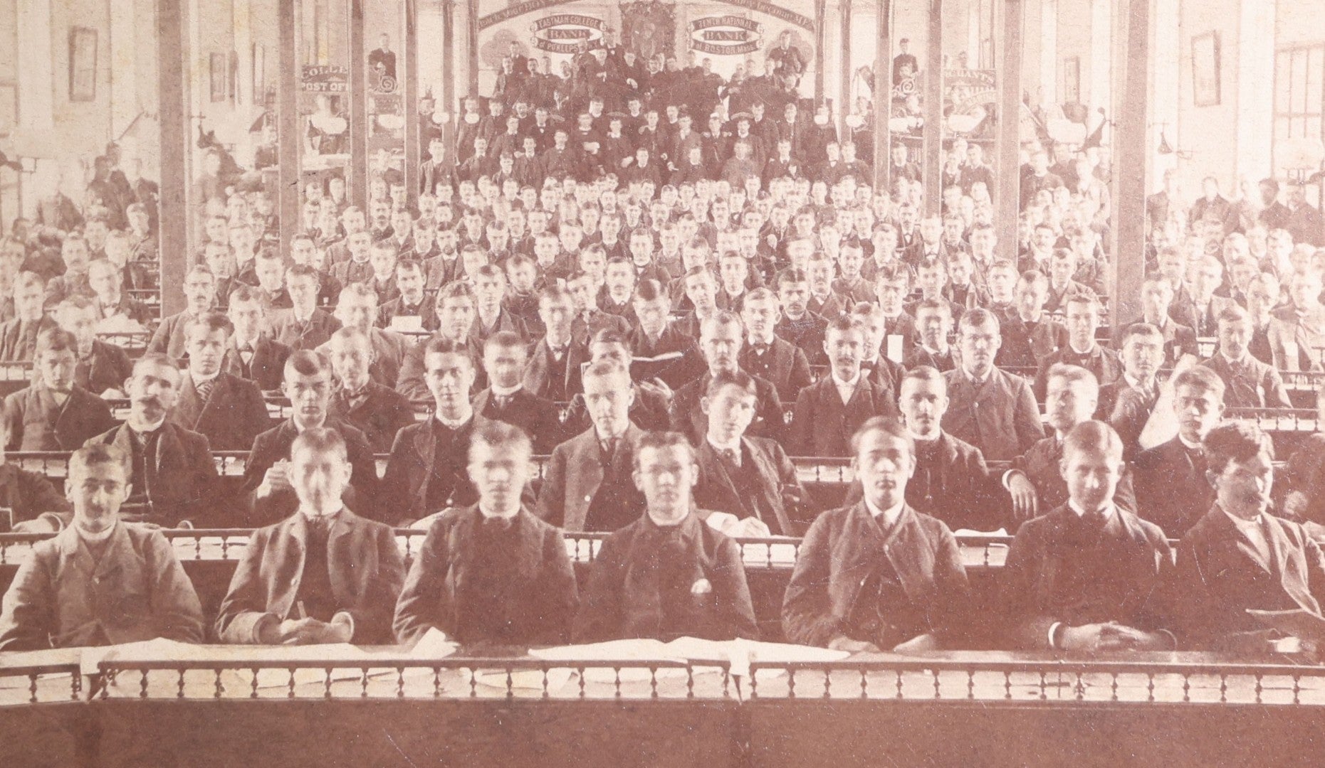Lot 132 - Antique Board-Mounted Photograph Of A Large Assembly Hall Interior With Rows Of Seated Young Men, Banners For Eastmore College, Bank Of Poughkeepsie, And Tenth National Bank Of Boston