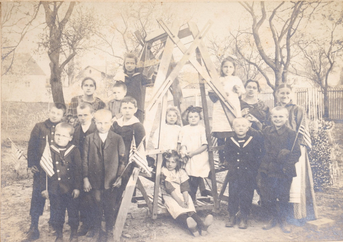 Lot 137 - Antique Board-Mounted Photograph Of A Group Of Children With American Flags Posed Around A Wooden Structure Outdoors