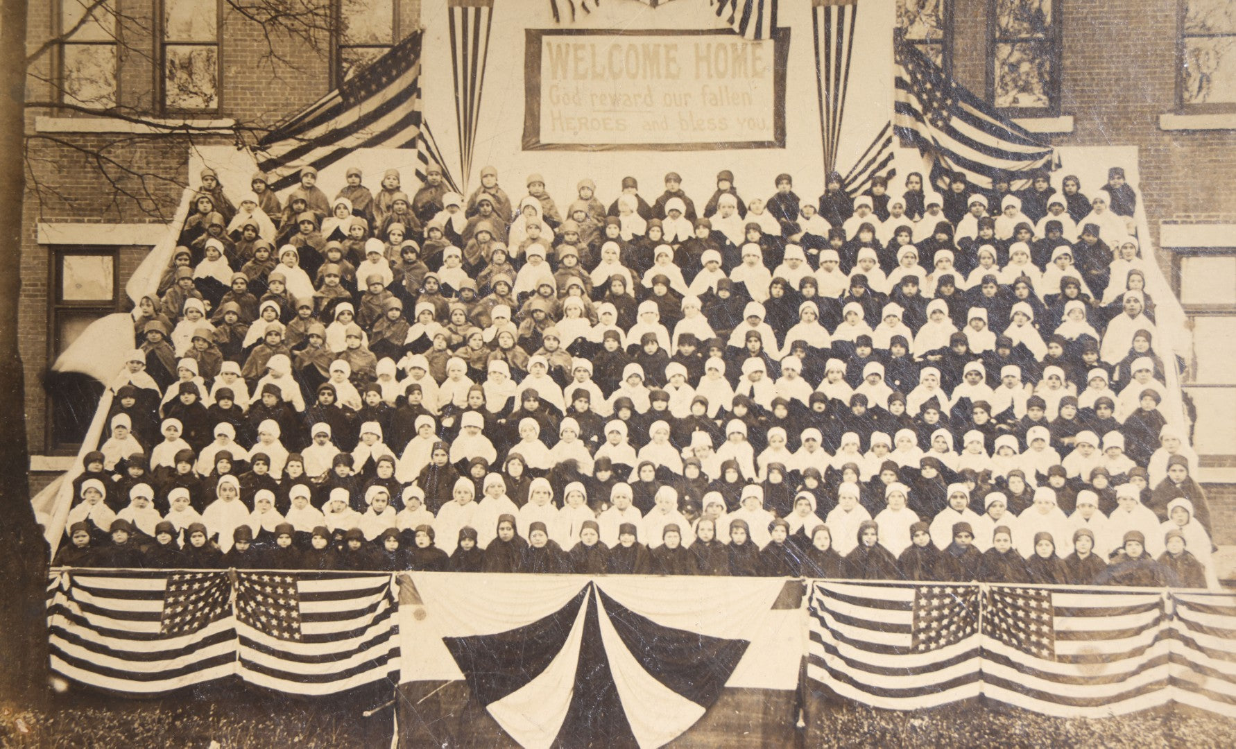 Lot 138 - Antique Board-Mounted Photograph Of Children Posed On Steps Of A Brick Building With WWI "Welcome Home" Banner, American Flags, And Patriotic Bunting, Photographed By Shea's Art Studio, Danbury, Connecticut