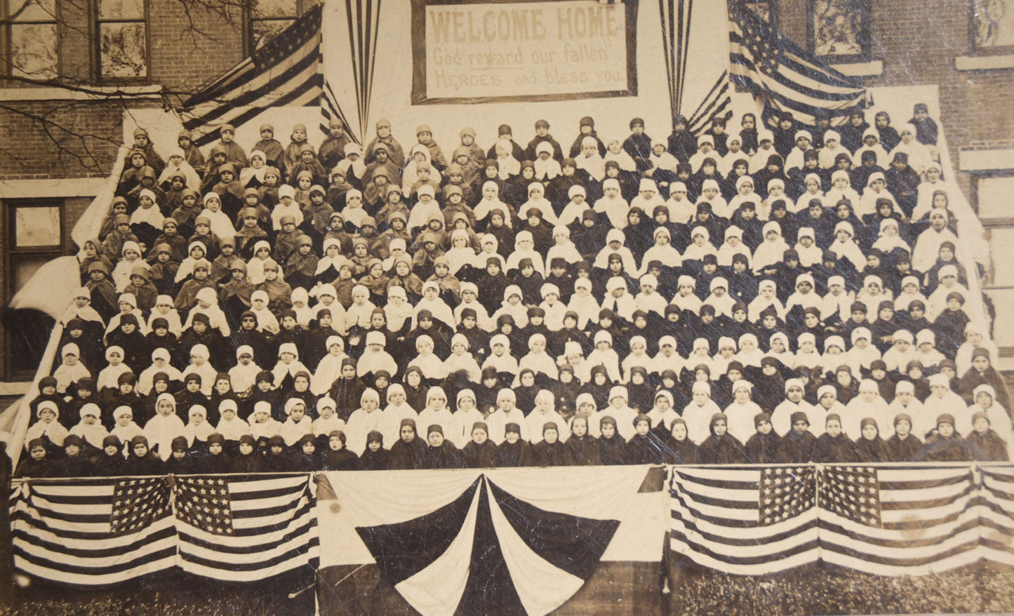 Lot 138 - Antique Board-Mounted Photograph Of Children Posed On Steps Of A Brick Building With WWI "Welcome Home" Banner, American Flags, And Patriotic Bunting, Photographed By Shea's Art Studio, Danbury, Connecticut