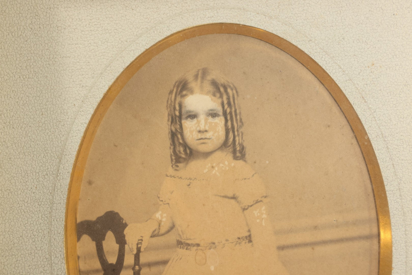 Antique Photograph of a Young Girl in a White Dress, Matted with Oval Gilt Opening, in Ebonized Inlaid Frame