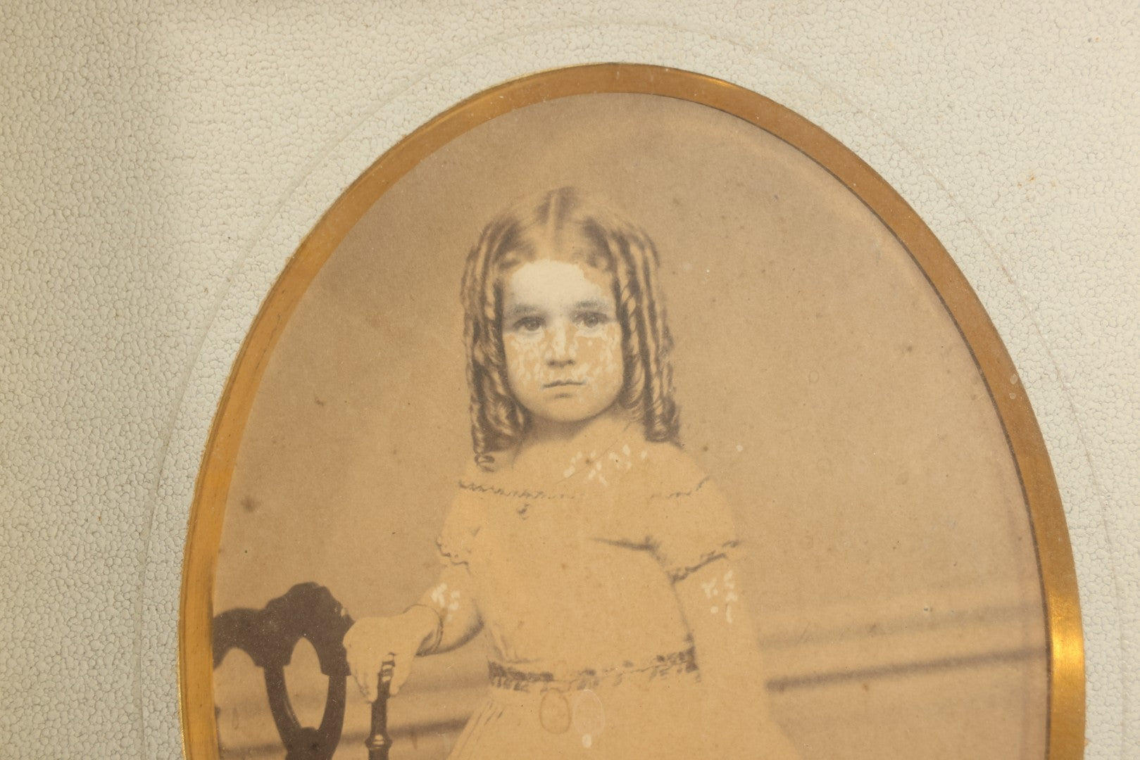 Antique Photograph of a Young Girl in a White Dress, Matted with Oval Gilt Opening, in Ebonized Inlaid Frame