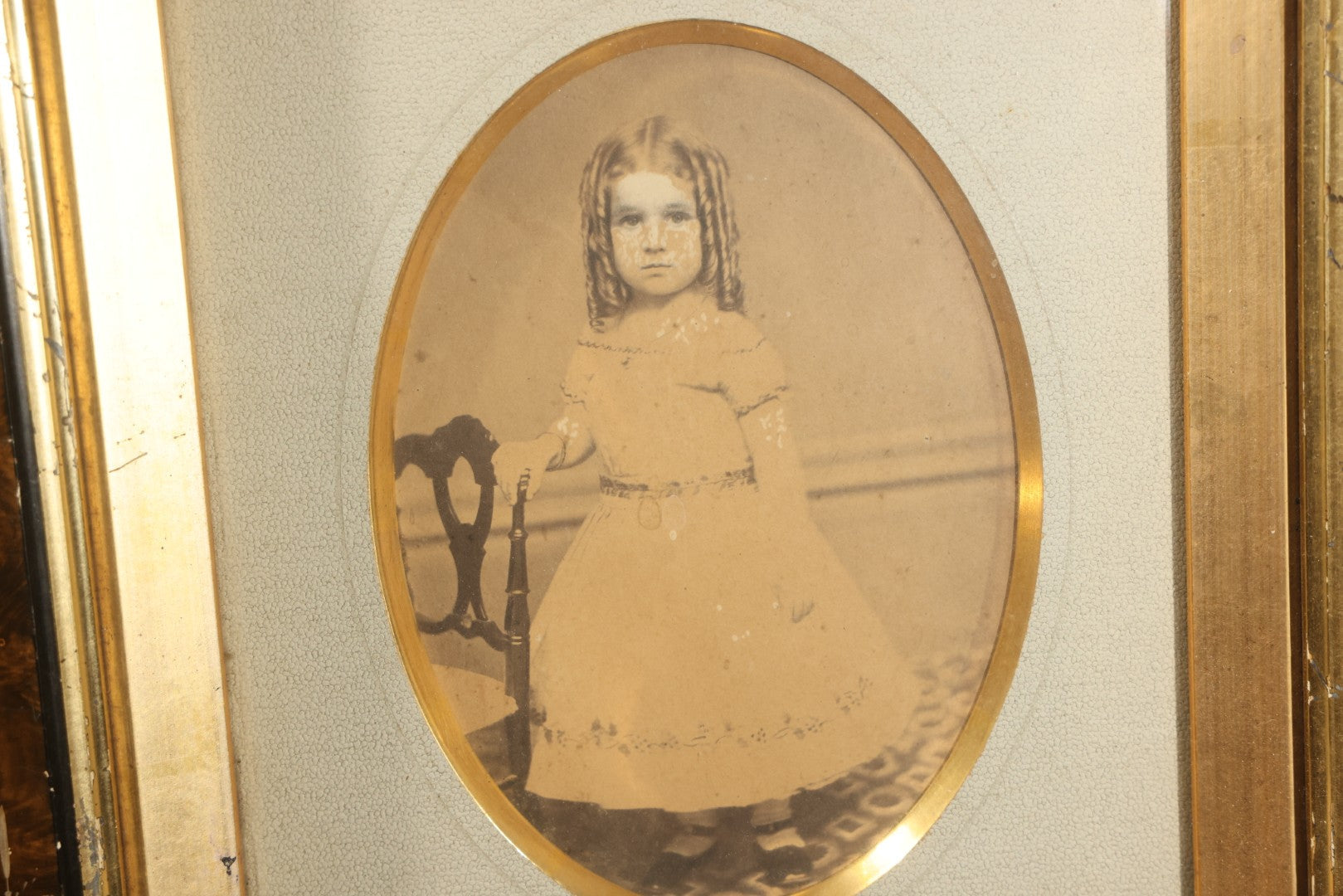 Antique Photograph of a Young Girl in a White Dress, Matted with Oval Gilt Opening, in Ebonized Inlaid Frame